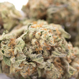 A dense frosty green astroboy thca hemp flower with orange pistils showcasing cosmic brand identity and sweet buttery notes