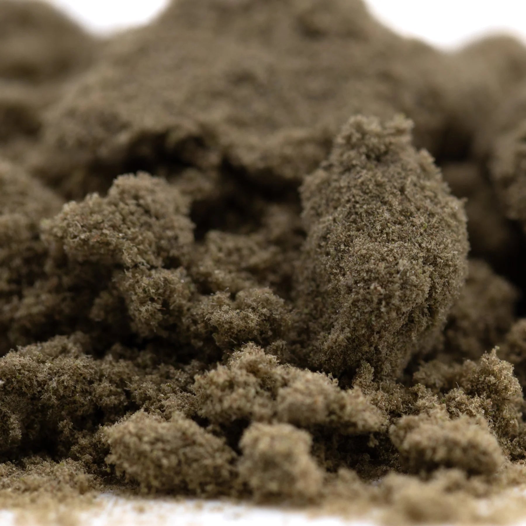 A mound of coarse dark brown banjerine thca kief with a textured surface showcasing paradoxical citrus wholesale positioning