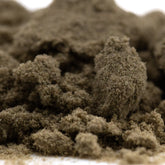 A mound of coarse dark brown banjerine thca kief with a textured surface showcasing paradoxical citrus wholesale positioning