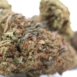 A dense resinous bubba kush cbd hemp flower with green and amber hues covered in fine trichomes highlighting cannabinoid potency and flavor profile