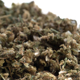 A dense textured indiana bubble gum cbd trim hemp flower bud with green and brown hues covered in fine trichomes