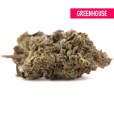 Green cannabis bud with white trichomes, purple hues, and Dough Boy’s Greenhouse label