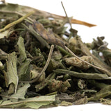A pile of dried greenish-gray thca trim wholesale sage leaves with fuzzy texture and stems from fornicate greenhouse cultivation