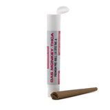 White cylindrical container labeled gas monkey thc-a premium pre-roll next to an unrolled brown paper joint for thca pre-rolls