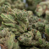 Close-up of vibrant green Ghost OG THCa Hemp Flower Smalls with white trichomes and orange pistils