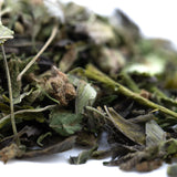 A pile of dried greenish-brown giggle gas greenhouse thca trim hemp flower with stems and textured surfaces