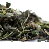 A pile of dried light green and gray greenhouse thca leaves with visible stems from giggle gas greenhouse hemp flower trim