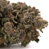 A dense greenhouse thca flower giggle gas premium hemp bud with frosty trichomes and green and brown hues