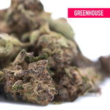 A dense halle berry thca greenhouse hemp flower bud with green and purplish hues covered in trichomes