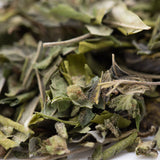 Dried green joker og greenhouse thca trim with fuzzy textured leaves and stems for mood elevation and amnesia haze effects