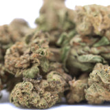 A pile of lemon cherry gelato thca hemp flower greenhouse smalls with green and brown hues covered in fine trichomes