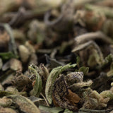 Dried mendo breath thca trim with green and brown hues covered in fine trichomes resembling vanilla caramel candy