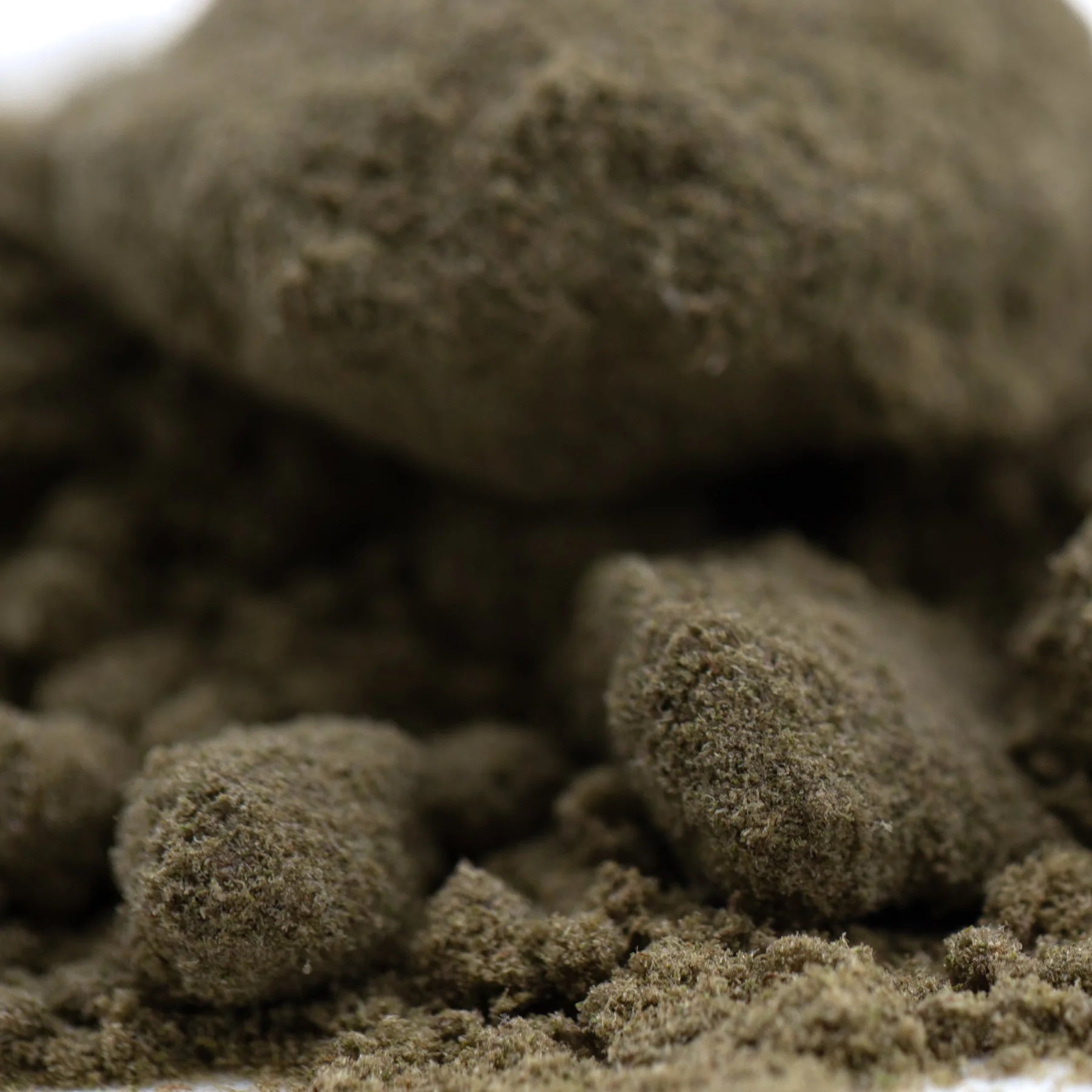 Dark brown textured fuzzy pellets of mendo breath thca kief from a cult classic hemp flower product for wholesale use