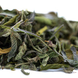 A pile of dried green nectarine jelly greenhouse thca trim hemp flower leaves with fuzzy texture and yellowish brown hints