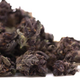 Dark crinkled green and brown dried tea leaves from purple queens thca smalls hemp flower hindu kush blend