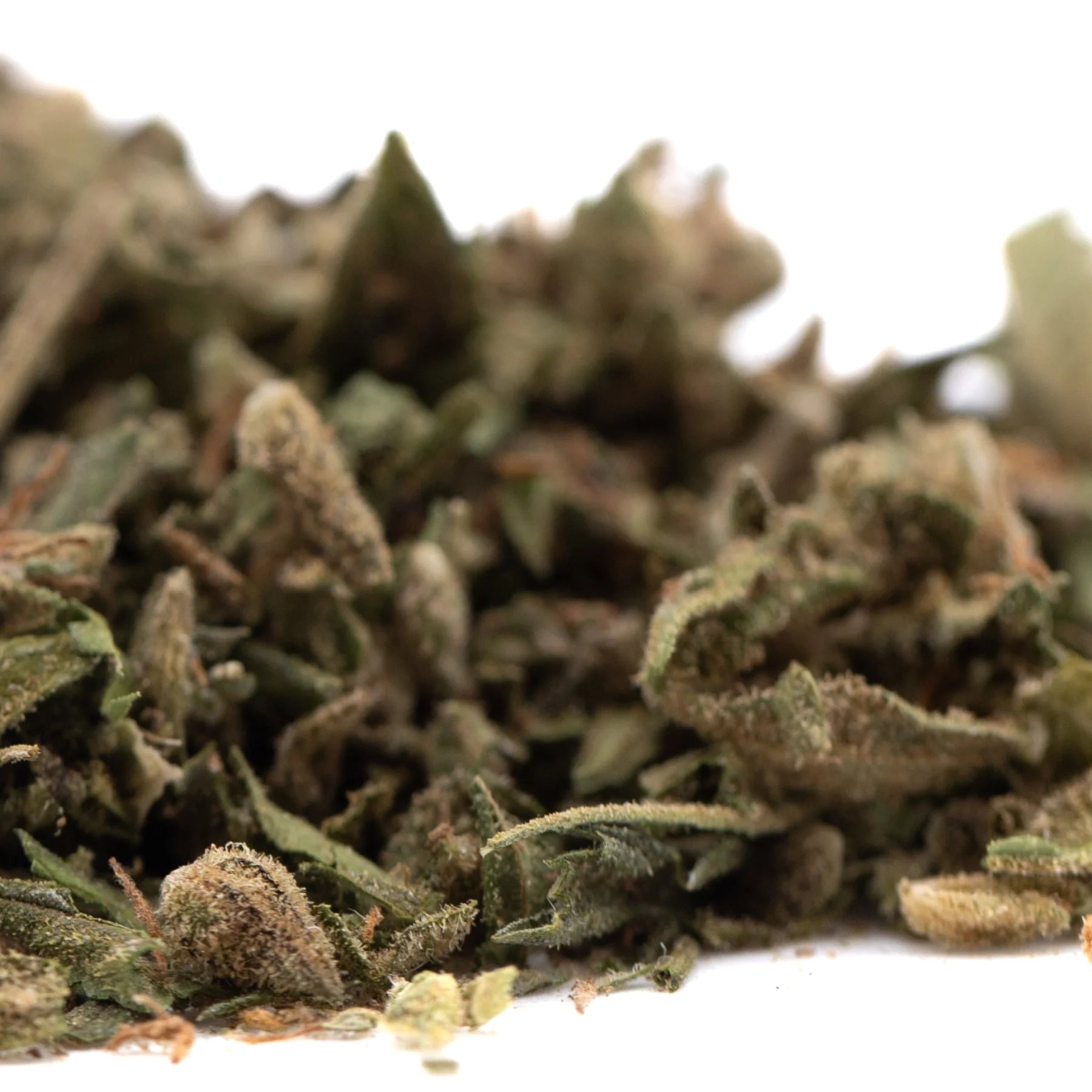 A pile of sour apple full-term thca trim with green and brown hues covered in fine trichomes from legendary genetics