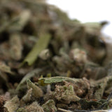 A pile of dried greenish-brown strawberry cheesecake thca trim wholesale with visible trichomes and leafy textures