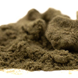 A mound of coarse earthy brown powder of strawberry cheesecake thca kief full-term with dessert flavor granules