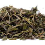 A pile of dried green and brown studio 54 greenhouse thca trim leaves with hints of white for cultural branding