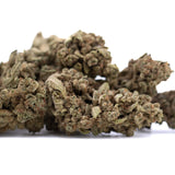 A dense turtle taffy thca flower bud with green and brown hues covered in fine trichomes from organic cultivation
