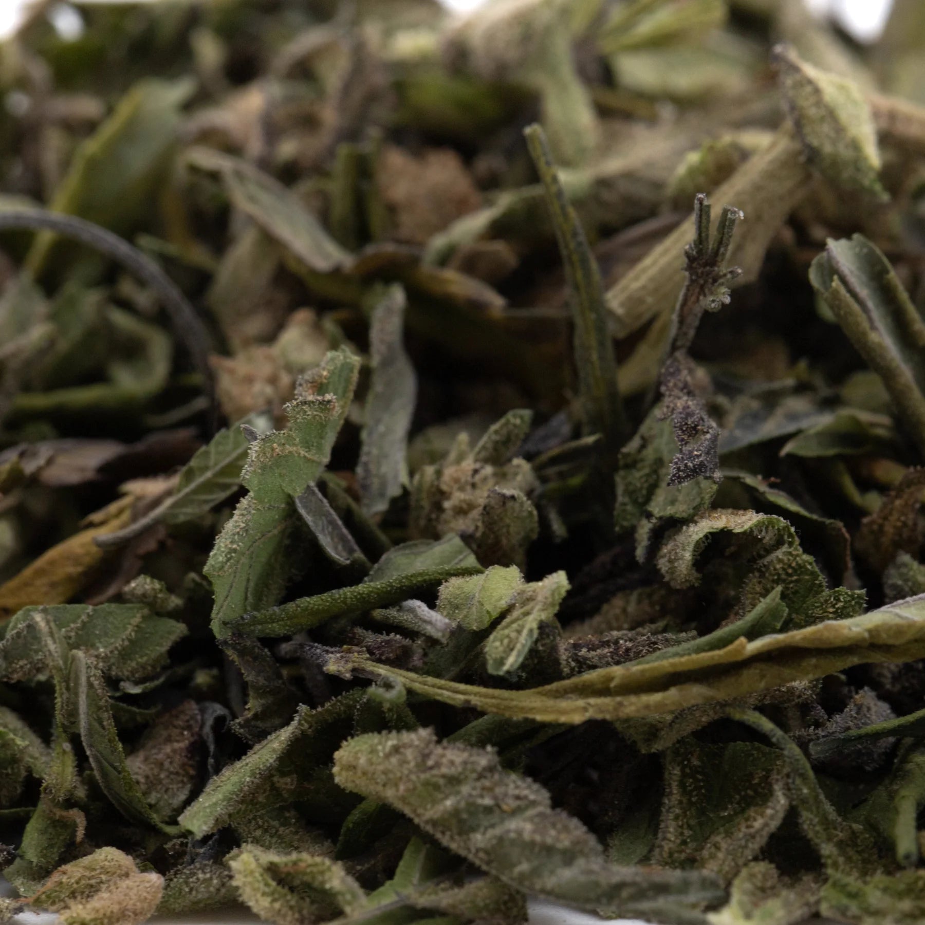 A pile of dried light green and pale yellow bahama bussdown hemp flower greenhouse thca trim with fuzzy texture
