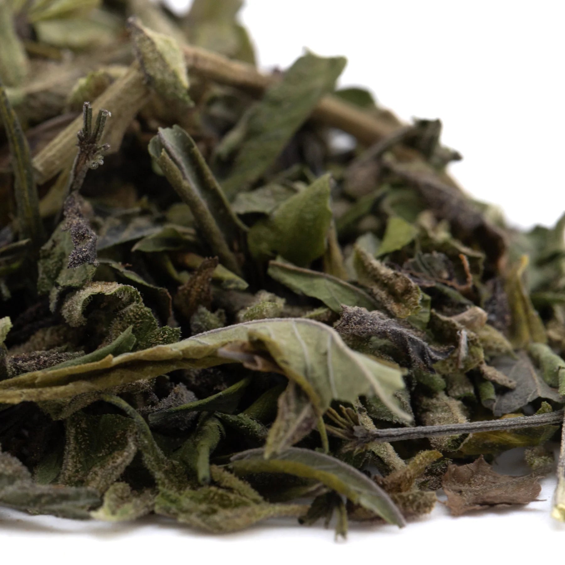 A pile of bahama bussdown greenhouse thca trim dried green hemp flower leaves with visible stems and brown edges
