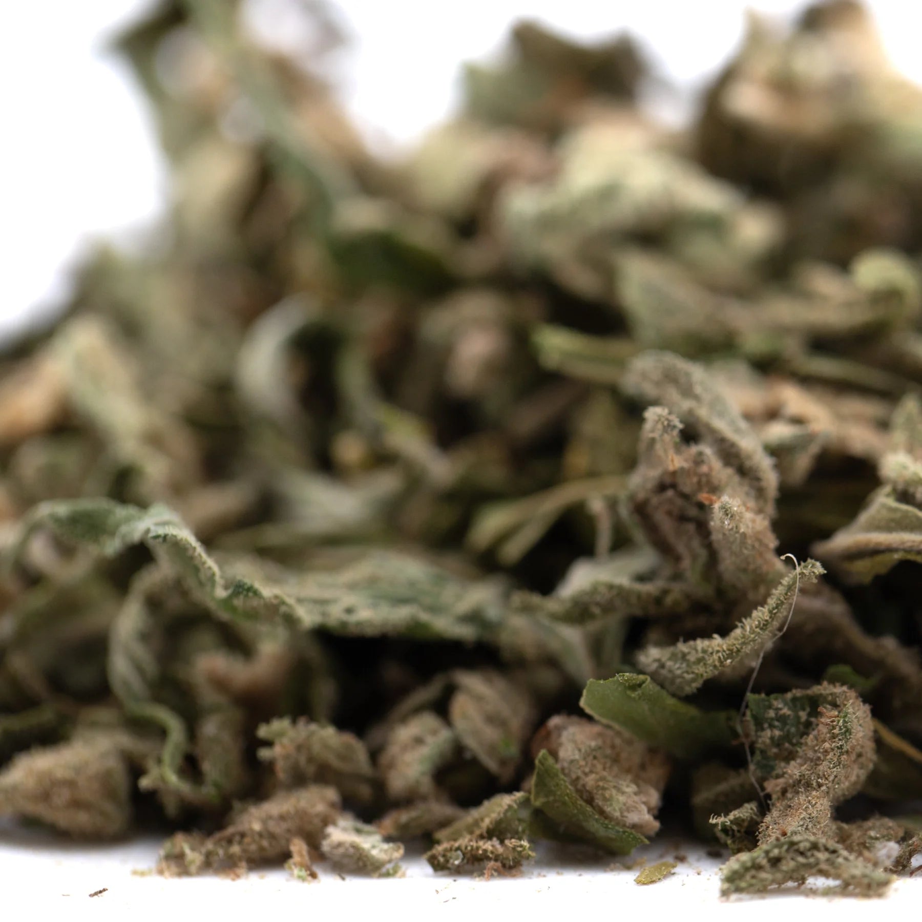 A pile of dried green and brown banana og full-term thca shake leaves showing cannabinoid content texture