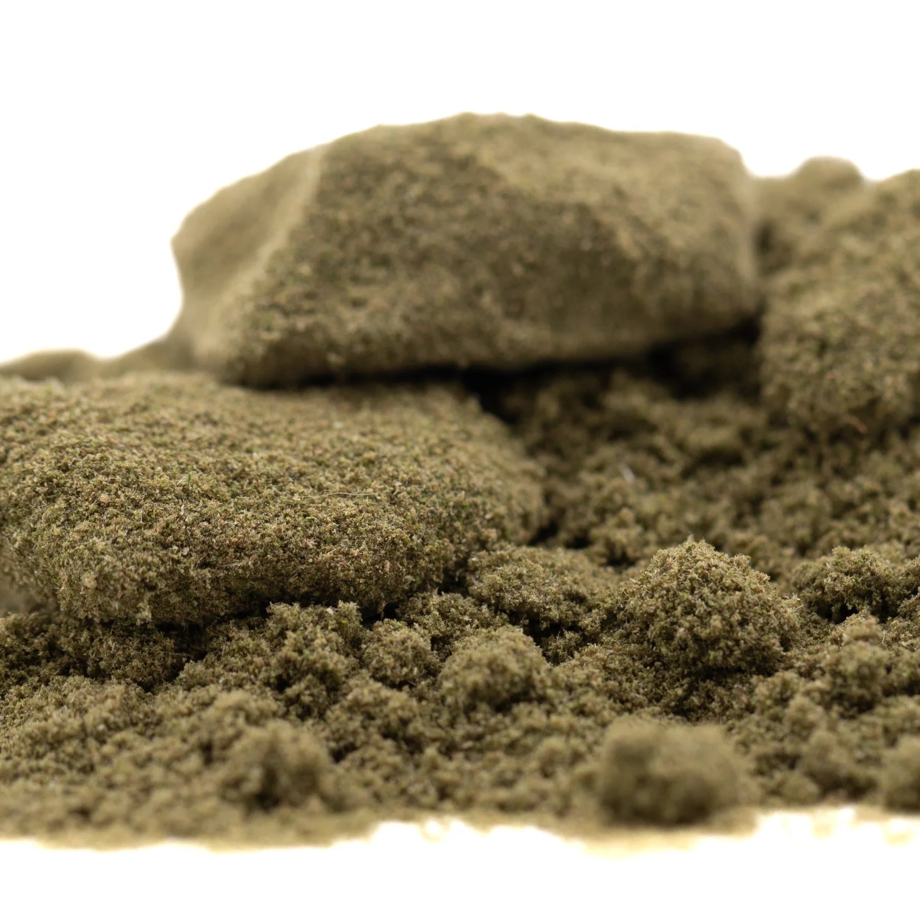 A mound of coarse greenish-brown thca kief with a larger rock, showcasing legendary banana og tropical character