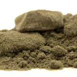 A mound of coarse greenish-brown thca kief with a larger rock, showcasing legendary banana og tropical character
