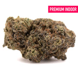 A dense black amber indoor thca flower bud with textured green brown and orange hues in an irregular shape