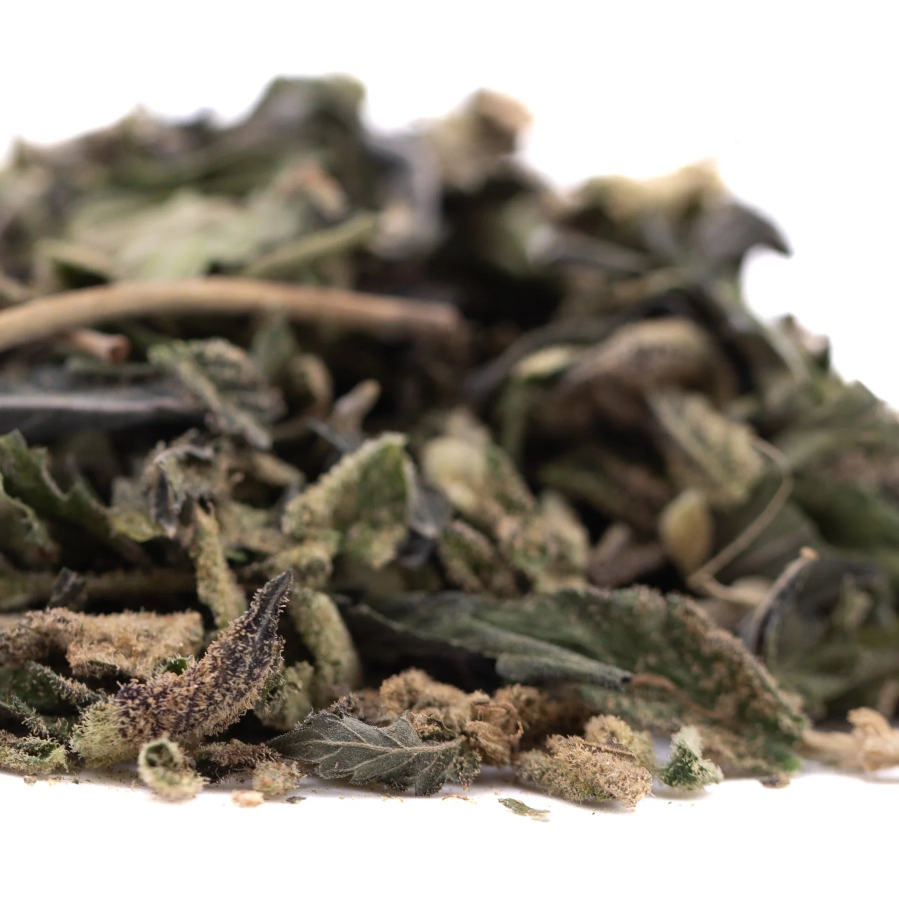 A pile of dried greenish-brown blue sugar’s greenhouse thca trim leaves with fuzzy textures and stems for sugar cookies