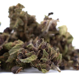 Dense dried bubba kush cbd smalls hemp flower with green and purplish hues and intricate leafy textures for afghani indica fans