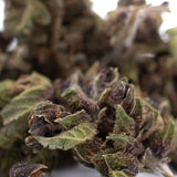 Dense resinous bubba kush cbd smalls hemp flower with green and purplish hues covered in fine trichomes afghani indica