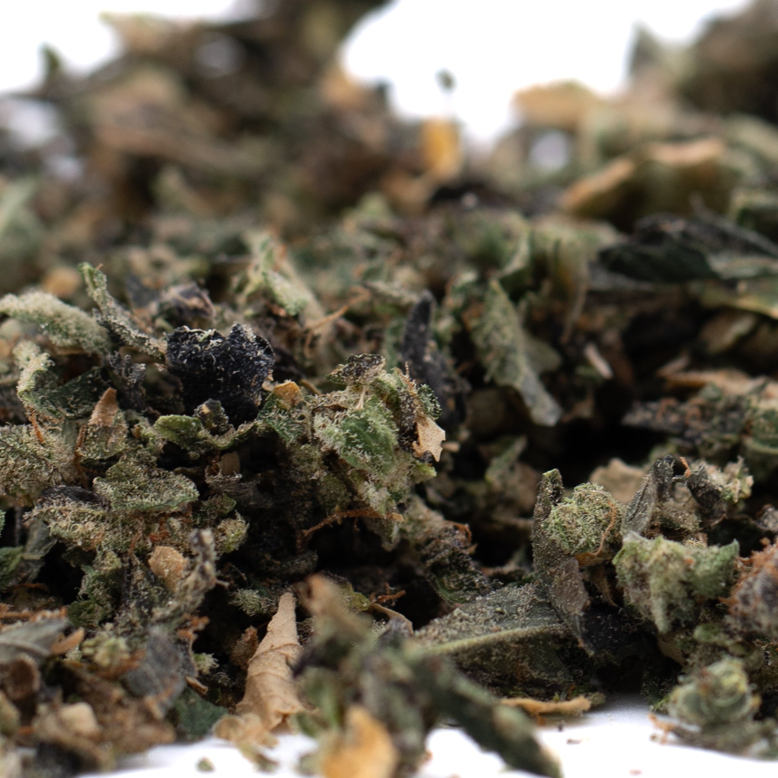 Close-up of finely ground Butter OG Indoor THCA Trim for Wholesale 1LB products