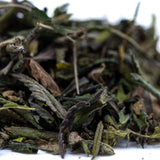 Dried green thca trim leaves with dark and light shades and slight curling edges from cali burger greenhouse triple-cross genetics