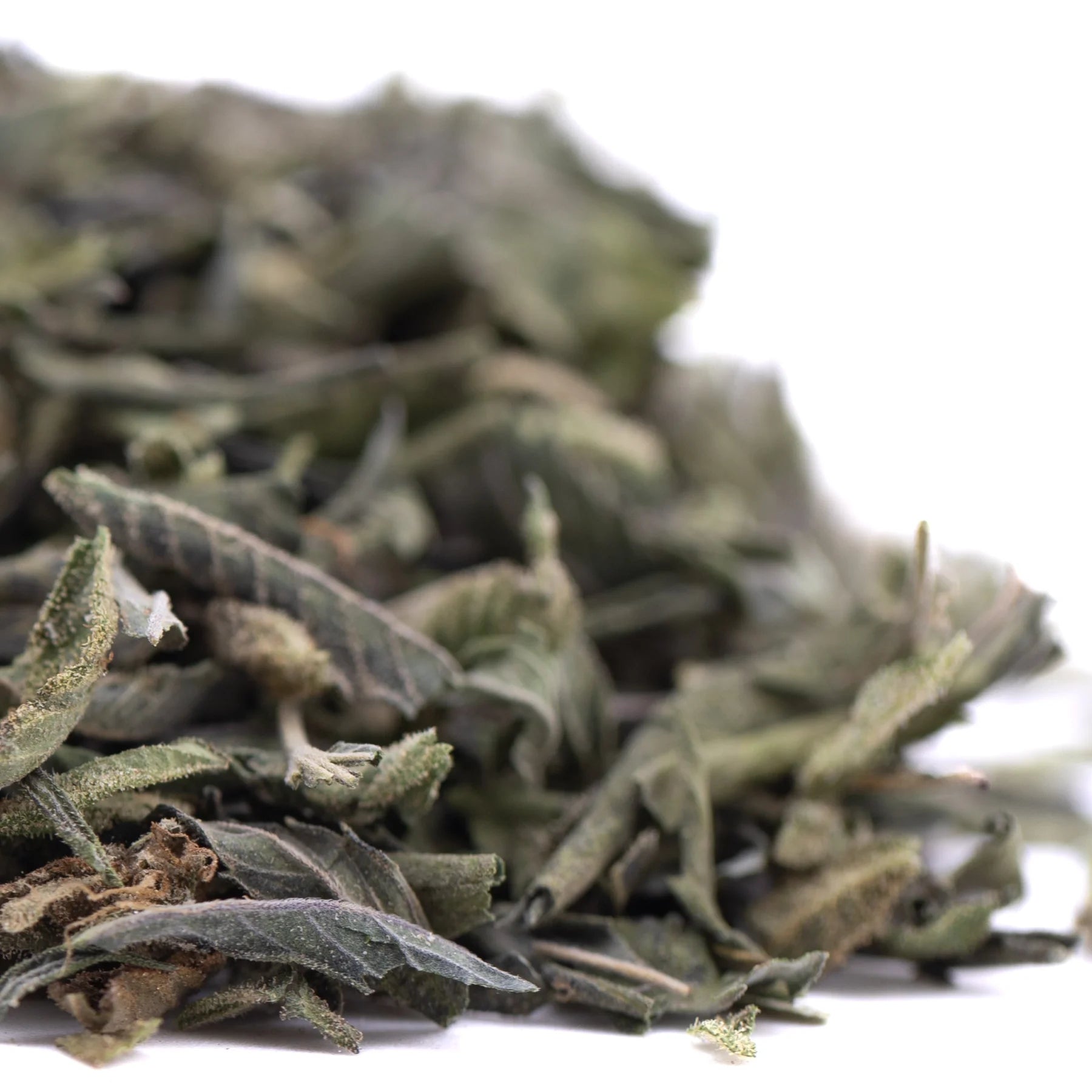 A pile of dried muted green and grayish sage leaves in candy pave greenhouse thca trim wholesale product form