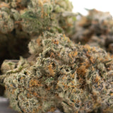 A dense green and orange-hued chicken and waffles indoor thca flower bud covered in trichomes for hemp flower wholesale