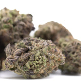 A dense textured greenhouse hemp flower bud with green and purplish hues covered in trichomes waffles thca