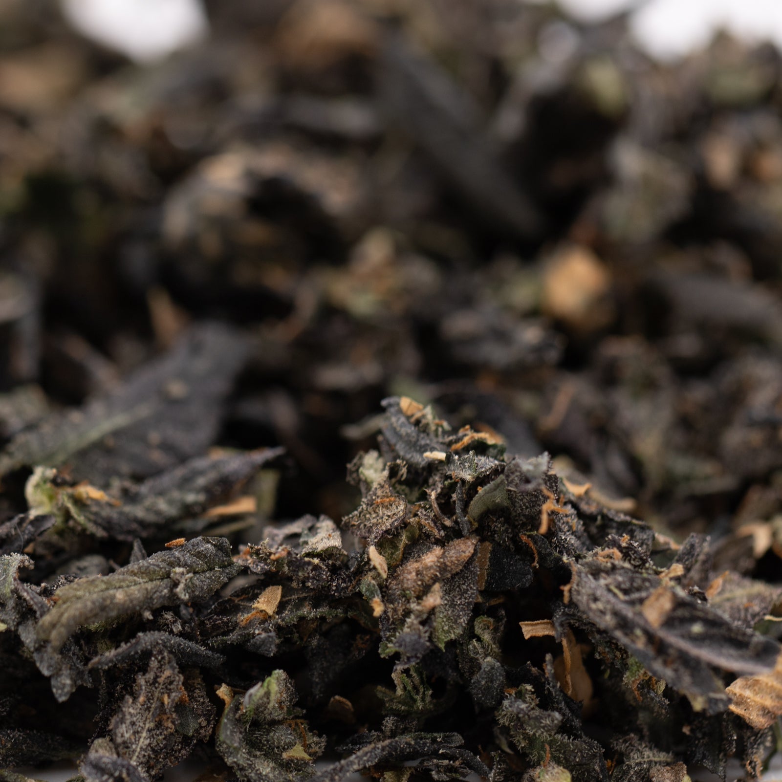 Loose dark dried tea leaves with lighter flecks for Chunky Monkey Indoor Trim Wholesale 1LB featuring Grape Ape, THCA Trim, Banana Kush