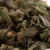 A close-up of cream caramel full-term thca trim hemp flower with green brown and purple hues covered in trichomes