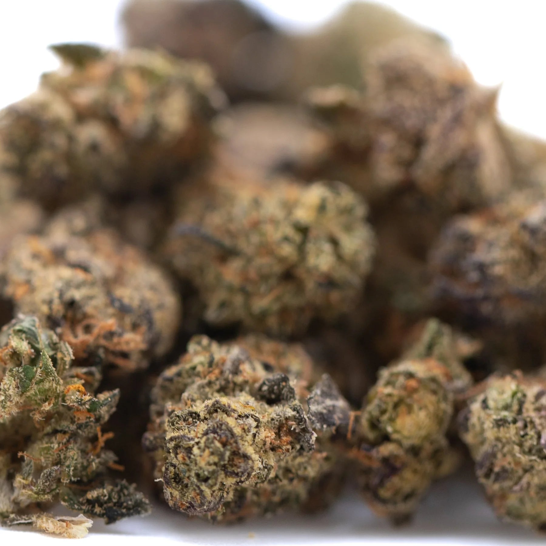 A pile of dense green and brown critical berries cbd smalls hemp flower buds with visible trichomes