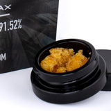 Black ceramic jar filled with golden orange dolato cbg dab wax concentrate 91.52 ideal plus 1g