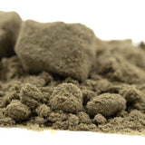 A mound of ultra-premium quantum thca kief coarse olive green sand with granular texture for face fat full-term use