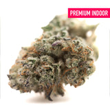 A dense flyin hawaiian indoor thca flower hemp bud with green and purple hues covered in trichomes and orange pistils