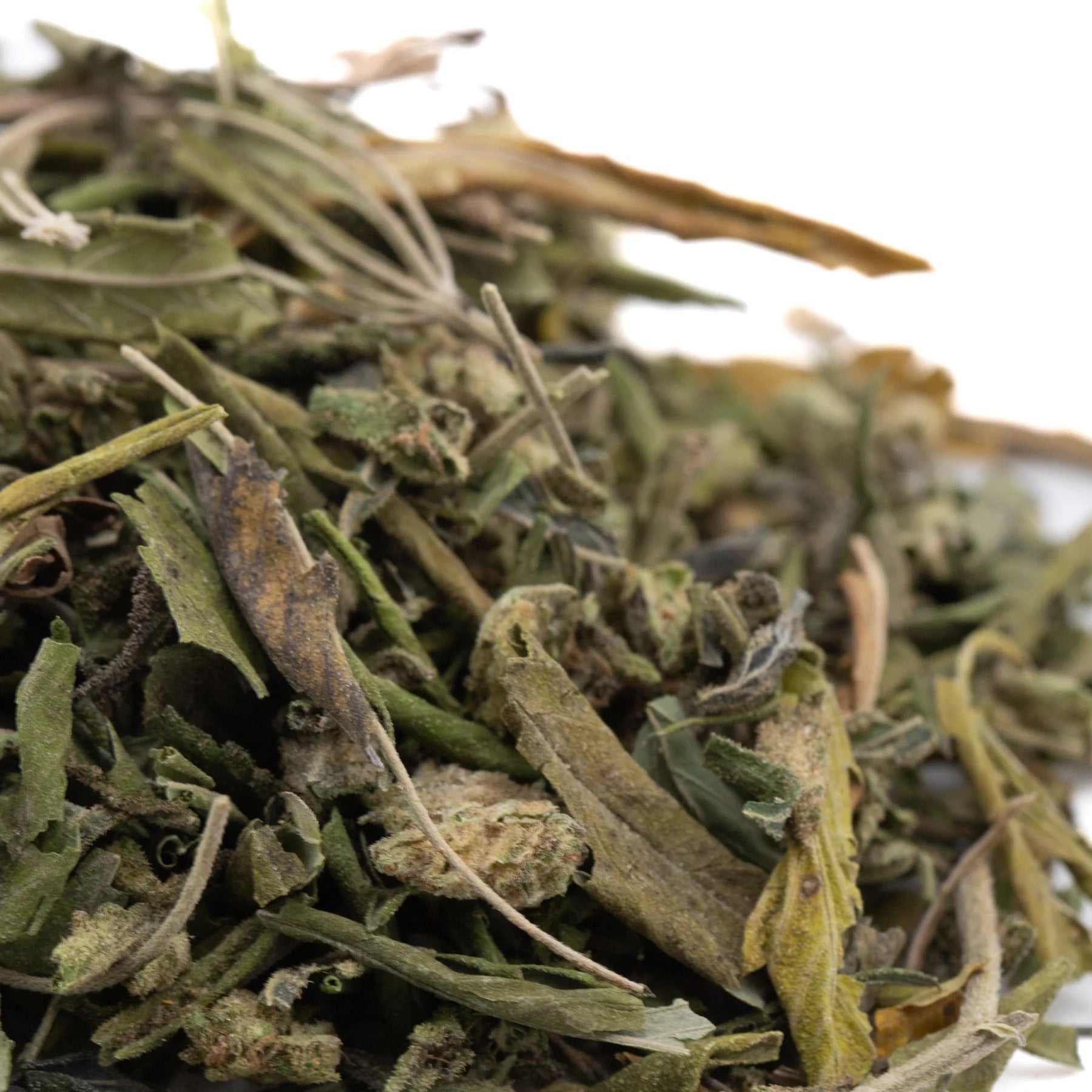 A pile of dried greenish-brown thca trim with yellow edges from obama kush greenhouse cultivation wholesale