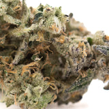 Dense frosty green fornicate indoor thca flower with orange pistils and dark trichomes featuring earthy gassy funk terpene profile