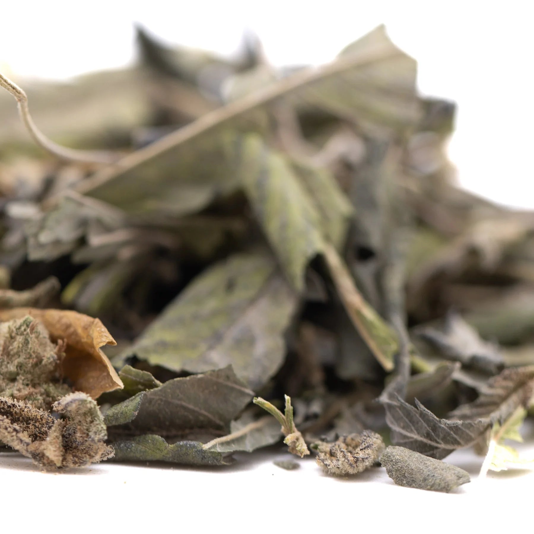 A pile of dried muted green and brown greenhouse thca trim wholesale with fuzzy stems kush phenotype leaves