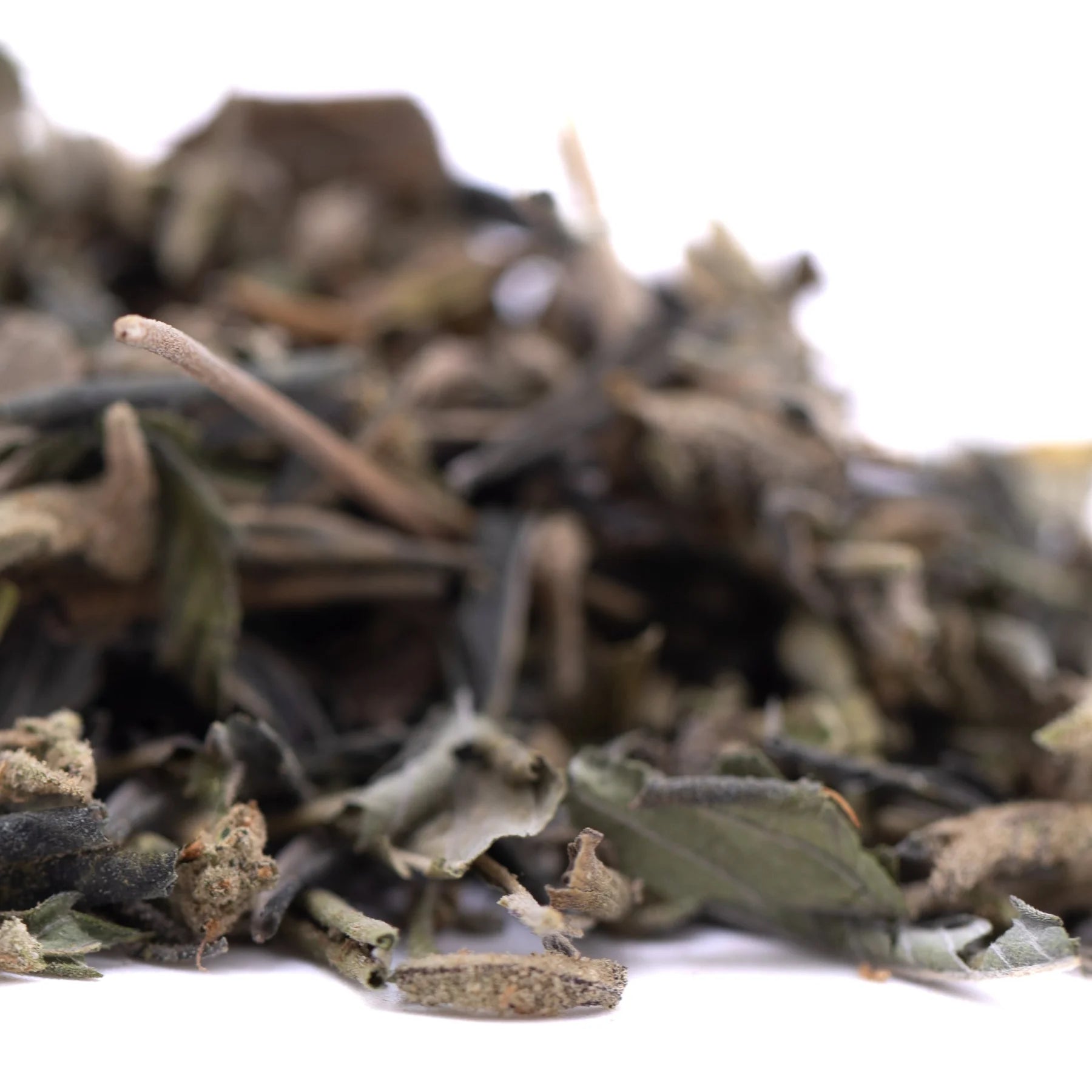 A pile of dried muted green and brown gassa purple’s greenhouse thca trim wholesale herbal leaves with small stems