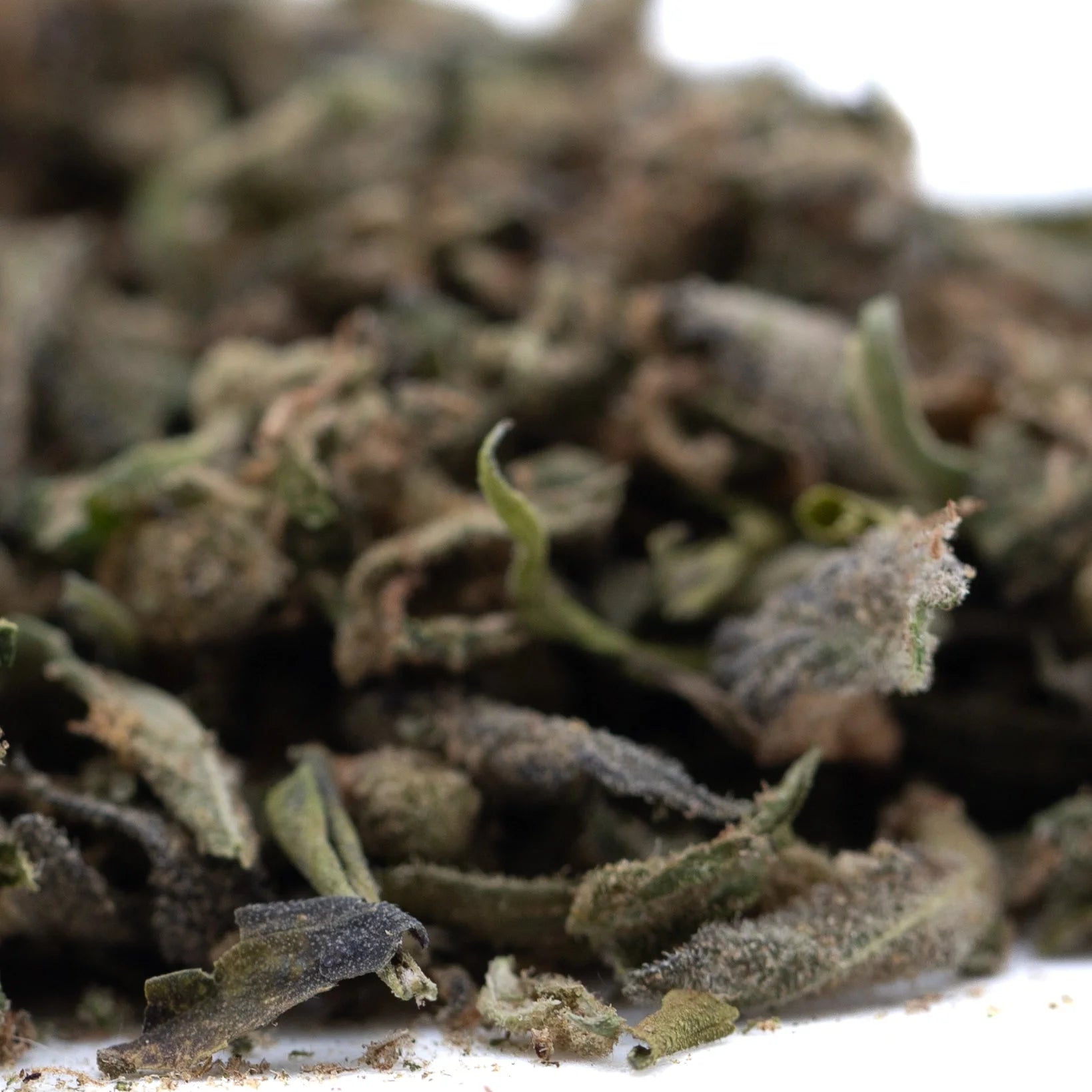 Dried green and brown chemdawg x gsc cannabis buds with visible trichomes in gmo full-term thca trim wholesale