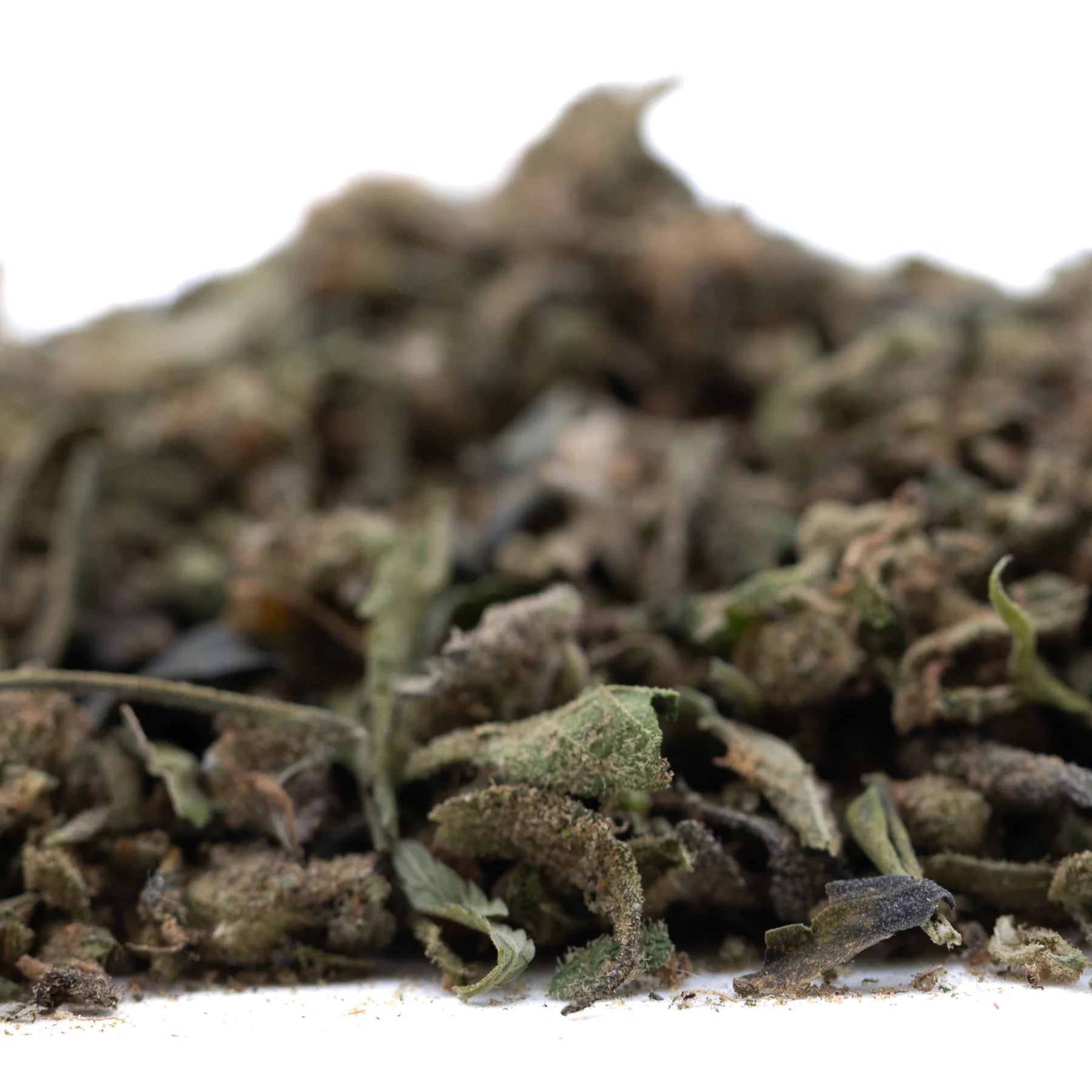 A pile of dried green and brown chemdawg x gsc full-term thca trim with pungent garlic aroma for wholesale use